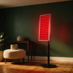 Best Red Light Therapy Panels 2026 Red LED therapy panel glowing on a stand in a minimalist room with a plant